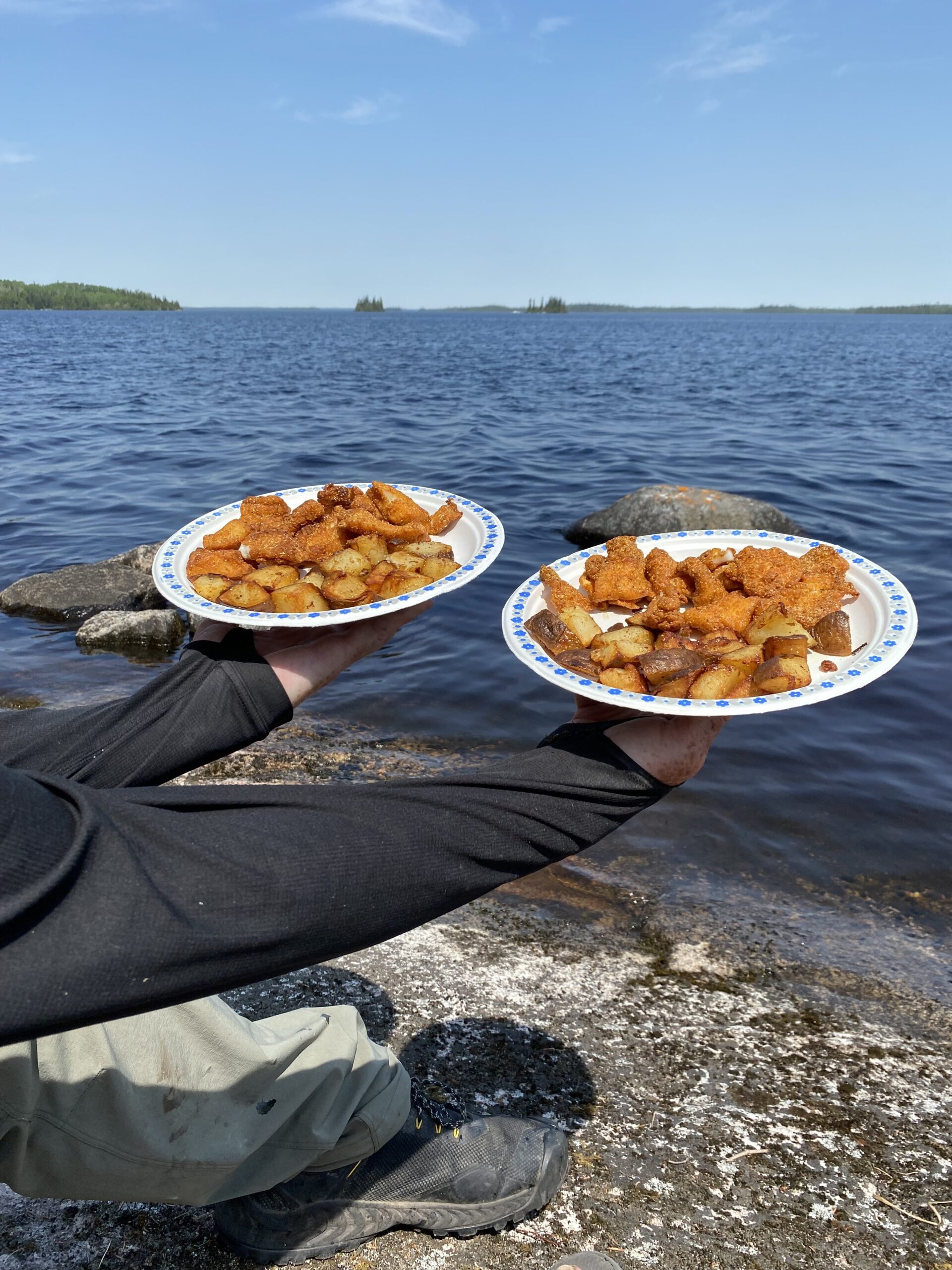 Shore lunch of fried walleye and potatoes on the rocks at Van Poele